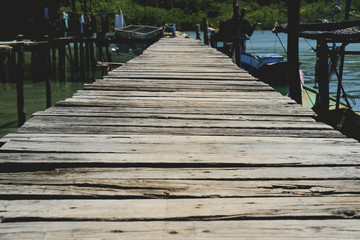 Fototapeta premium Walkway wood in village on sea with sunlight