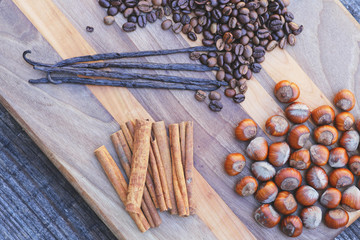 Vanilla and cinnamon sticks,with coffee beans and hazelnuts on wooden board