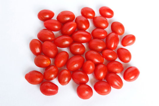 petites tomates cerise allong&eacute;es bien rouge et fraiche en groupe sur fond blanc