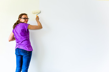 Woman painter working on house renovation. Painting wall with paint brush.