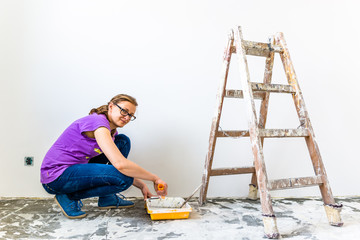 Naklejka premium Woman painter working on house renovation. Painting wall with paint brush.
