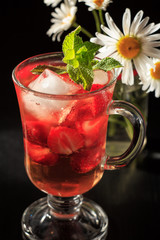 Carbonated lemonade with strawberry slices and mint with flowers of chamomile
