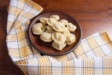 Boiled Ukrainian meat dumplings or ravioli on wooden background.