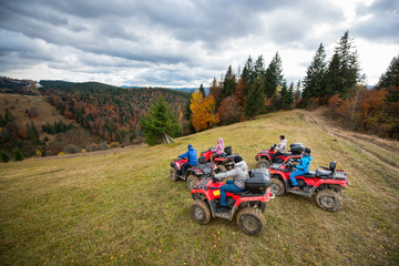Group of five people driving quad bikes on the hillside at the background of autumn forest with colorful trees and mountains. Top view © anatoliy_gleb