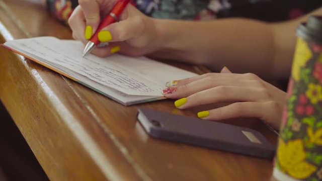 Women's hands writing something in a notebook