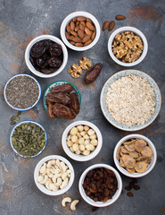 Ingredients for homemIngredients for homemade granola, oats, different nuts and raisins, dates, seed on the grey stone background, top viewade granola on the grey