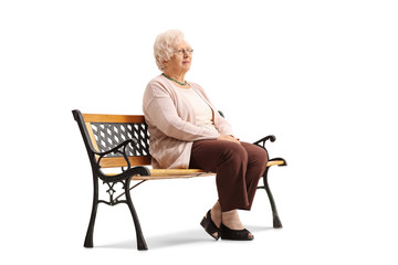 Elderly woman sitting on a bench and looking away - Powered by Adobe