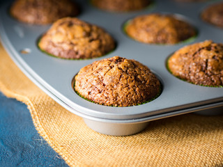 Banana chocolate muffins with caramel sugar topping on dark background