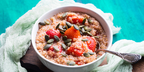 Quinoa porridge with strawberries and pumpkin seeds in bowl. Light dairy and gluten free breakfast