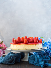 Home made strawberry baked cheese cake on gray background with flowers