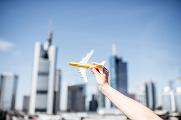 Holding a toy airplane on Frankfurt cityscape background. Frankfurt has a very large airline connection in Europe