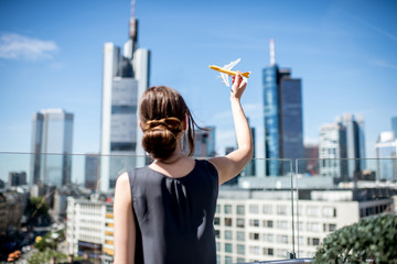 Young woman playing with toy airplane on the modern cityscape background in Frankfurt. Air...