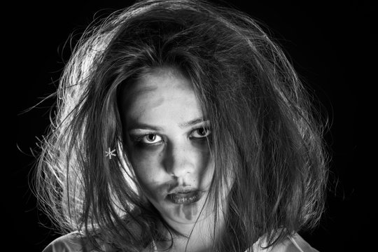 pretty fun crazy girl with fluffy hair and smeared cosmetics on black background, monochrome