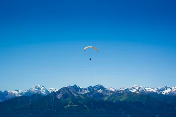 Tuinposter Yellow Paraglider over the Europe Alps mountains © liptoncnx