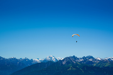 Fototapeta na wymiar Yellow Paraglider over the Europe Alps mountains