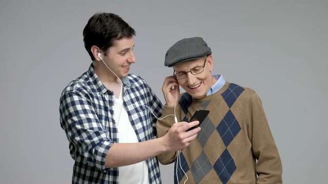 Young man and a senior listening to music on a phone