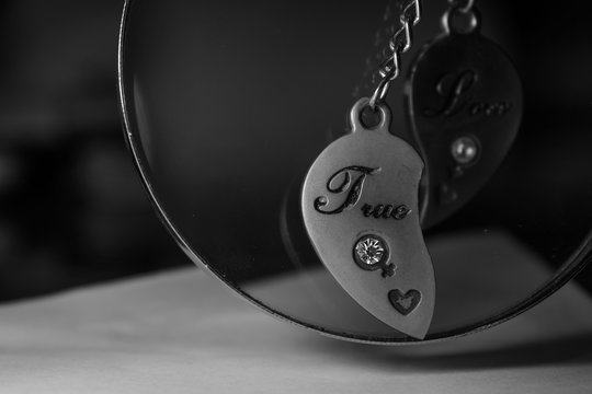 Half of the love medallion with the inscription "True". In black and white tones.