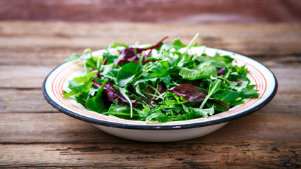 Fresh Green Mix Salad on Vintage Wooden background in a metal bowl.Leaves Of Spinach,Arugula,Romaine,Lettuce.Concept of Healthy Food.Vegetarian.Copy space for Text. selective focus.