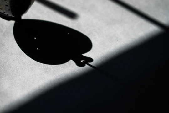 A shadow in the shape of a heart from a locket on a white sheet of paper.