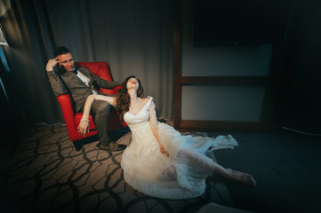 Stylish bride and groom posing on a chair in hotel. Movie
