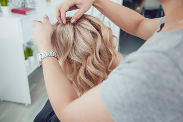 Hair stylist makes a curls for a girl, using hair styling. Hairdresser at work.