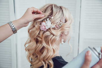 Hair stylist fixes the styling with a hair spray. Hairdresser at work.