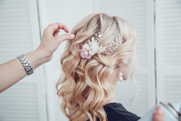 Hair stylist fixes the styling with a hair spray. Hairdresser at work.