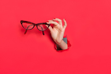 Female hand in paper hole with glasses