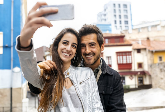 Smiling couple taking a selfie in the city