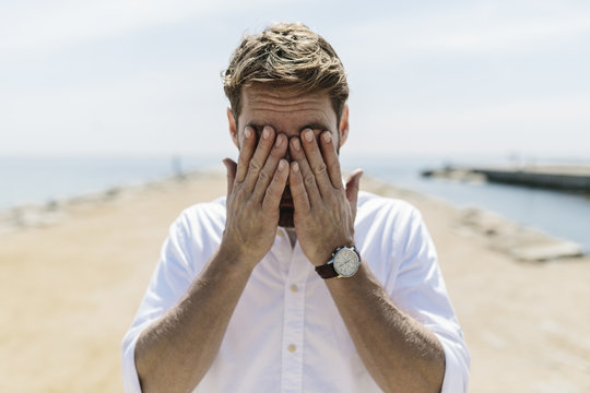 Mid adult man on the beach covering eyes