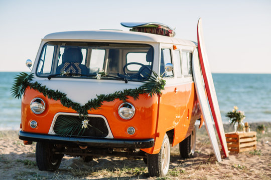 bus with a surfboard on the roof is a parked near the beach