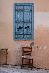 Fototapeta na wymiar Chair and a window of an old building in the old town of Athens, Greece. 
