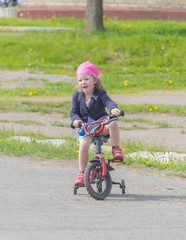 Fototapeta na wymiar on the Playground the child rides the girl on the bike.