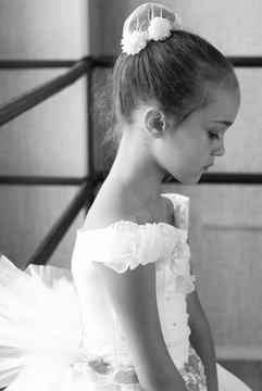 Young and beautiful ballet dancer posing in dance studio. Black and white art photo with bokeh and grain