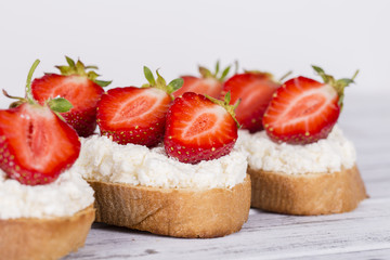 Sandwich of strawberry and cottage cheese on the wooden table, close up