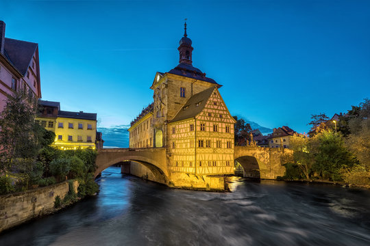 Bamberg. Illuminated building of Old Town Hall of Bamberg (Altes Rathaus) with two bridges over the Regnitz river in the evening, Germany