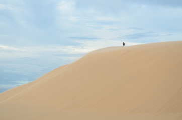 Fototapeta na wymiar Woman standing on sand moutain, white desert, Mui Ne, Vietnam.