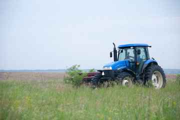pasture mowing with blue tractor and mower