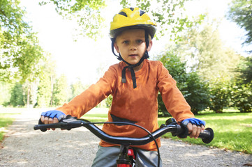 Obraz premium Boy ride a bicycle in city park 