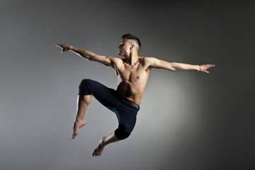 Fototapeta na wymiar Caucasian man gymnastic leap posture on grey background