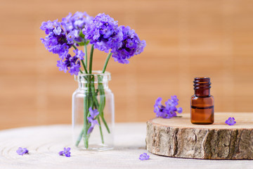 lavender essential oil in a brown glass bottle and fresh lavender flowers on brown background