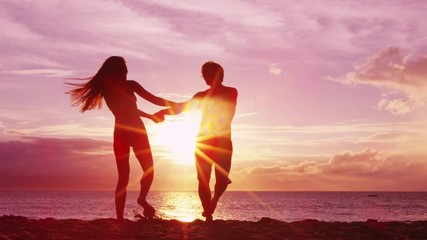 Romantic couple dancing on beach having fun at sunset playful and happy on honeymoon travel travel vacation holiday. Happy joyful lovers swirling around together. - Powered by Adobe