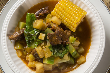 South American cuisine: Puchero soup with chickpeas close-up in a pot on the table.