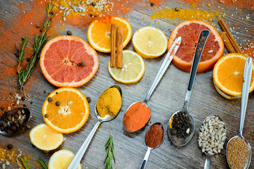 the fragrance of spices, red pepper, black pepper, mustard,sunflower seeds ,and orange slices of citrus fruits on dark wooden background of the table.