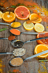 the fragrance of spices, red pepper, black pepper, mustard,sunflower seeds ,and orange slices of citrus fruits on dark wooden background of the table.