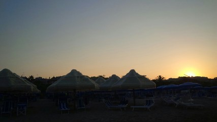 tramonto sulla spiaggia, dietro gli ombrelloni