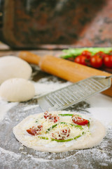 Cooking process of mini pizza with asparagus, tomatoes and cheese.
