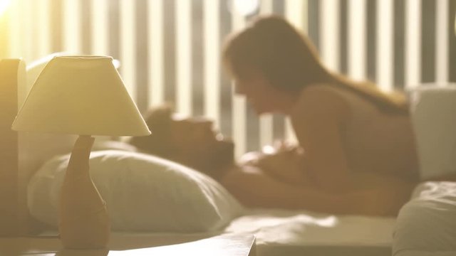 The bedside lamp on the background of the kissing couple