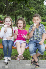 Fototapeta na wymiar In the summer in the park, children sit on a bench and eat ice cream.