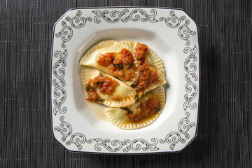 Dumplings with meat with tomato on a plate - Pierogi